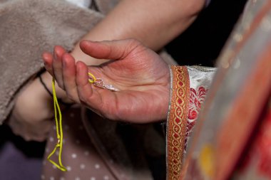 Papazın elinde vaftiz ayini için haçlar var..