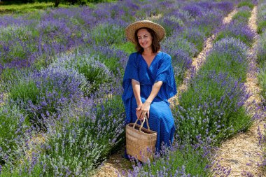 Mavi elbiseli ve hasır şapkalı kızlar mor lavanta çiçekleriyle tarlada fotoğraflanırlar.