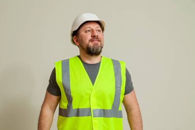 Çelik yelek ve farklı pozlarda beyaz miğfer giyen bir işçi beyaz arka planda duruyor.