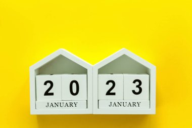 2023 numaralı tahta beyaz küpler. Sarı arka planda mutlu yıllar. Mutlu Noeller ve yeni yıl konsepti..