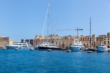 Diğer teknelerin arka planında özel kullanım için beyaz renkli yüksek hızlı bir gemi..