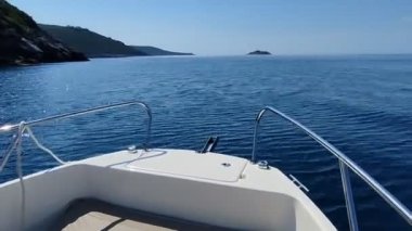 Mavi denizde beyaz bir motorlu tekne yüksek hızda ilerliyor.