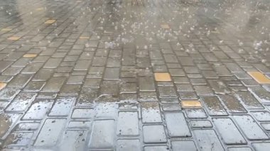 Bulutlu bir sonbahar gününde kaldırım taşlarına yağmur damlaları düşer..