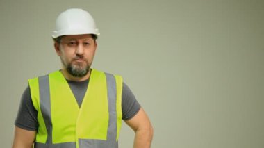 Yelek ve beyaz miğfer takan bir işçi beyaz arka planda farklı pozlarda el hareketlerini gösteriyor.