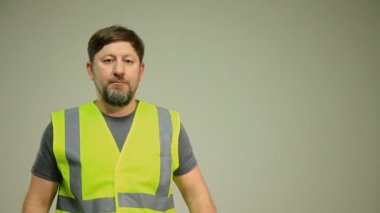 Yelek ve beyaz miğfer takan bir işçi beyaz arka planda farklı pozlarda el hareketlerini gösteriyor.
