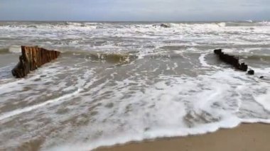 Hızlanan deniz dalgaları suyu bulandırıyor ve kumlu sahile atılıyor.