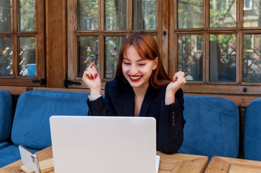 Kız video bağlantısıyla konuşuyor. Siyah takım elbiseli bir kız, bir kafede dizüstü bilgisayarında farklı duygular gösteren bir video bağlantısıyla konuşuyor..