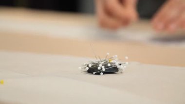 Bu yakın çekim bir mıknatıs tutacağında terzinin çalışma tablosuna karşı düzgünce dizilmiş dikiş iğnelerini yakalar. Bir terzi ya da terzinin titiz aletlerini sergilemek için mükemmel. Bu fotoğraf giysi yapımında kullanılan temel öğeleri vurgular.