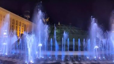 Şehrin mavi ışıklarla aydınlatılmış fıskiyesinin büyüleyici gece görüntüsü çarpıcı bir görsel etki yaratıyor. Su, karanlık gökyüzüne doğru ışıl ışıl parlıyor. Şehir mimarisini vurguluyor..