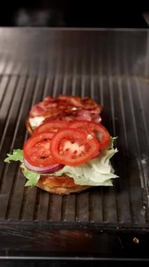 Mükemmel katmanlı bir burger: Kızarmış çörek, marul, domates, soğan, kıtır pastırma, çedar peyniri, sulu köfte ve turşu. Lezzet ve tazelikle doldurulmuş bir gurme yaratımı