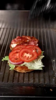 Lezzetli bir burger: sulu sebzeler, çıtır pastırma ve ızgarada taze salata. Taze yemek, iştah ve yemek pişirme becerileri..