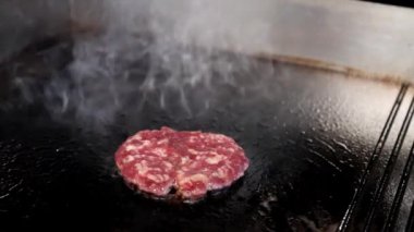 Izgara tavada köfte pişirme süreci. Buhar etin üzerine yükselir, iştah ve aşçılık becerisi ortamı yaratır..