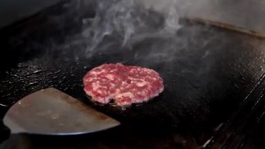 Sulu ızgara et burger: şef köfteyi çevirir ve peynir ekler, mükemmel hamburgeri yaratır. Fast food ve restoran reklamları için harika..