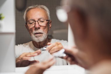 Yaşlı adam banyoda tırnaklarını kesiyor..