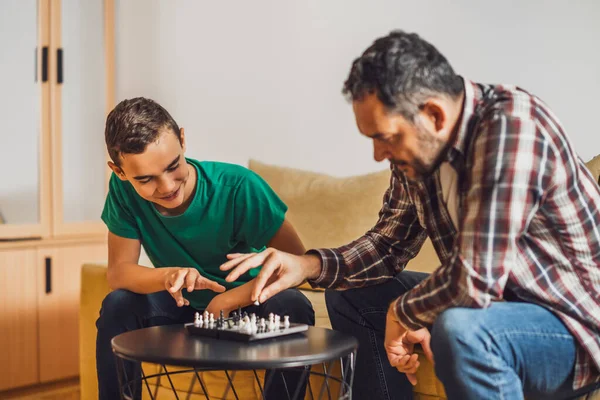 stock image Father and son are playing chess at home.