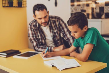 Baba oğluna öğrenmesinde yardım ediyor. Birlikte ödev yapıyorlar..