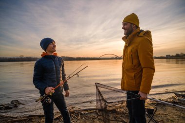 Father and son are ready for fishing on winter day. River fishing.