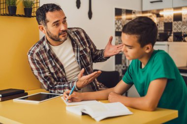 Baba oğluna öğrenmesinde yardım ediyor. Birlikte ödev yapıyorlar..