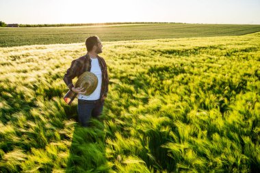 Çiftçi arpa yetiştiriyor. İyi bir sezon geçirdiği için memnun..