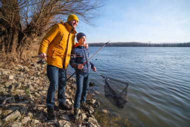Father and son are ready for fishing on winter day. Freshwater fishing.