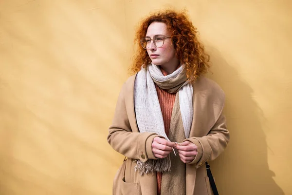 Natural portrait of pensive caucasian ginger woman with freckles and curly hair.