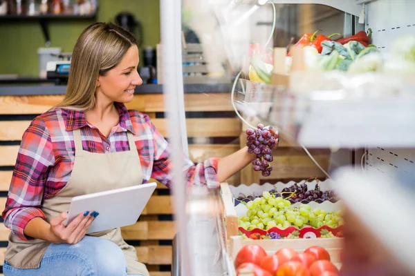 stock image Woman works in fruits and vegetables shop. She is examining goods.