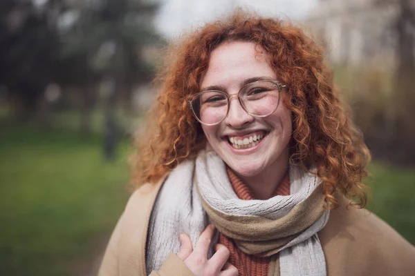 Natural portrait of smiling caucasian ginger woman with freckles and curly hair.