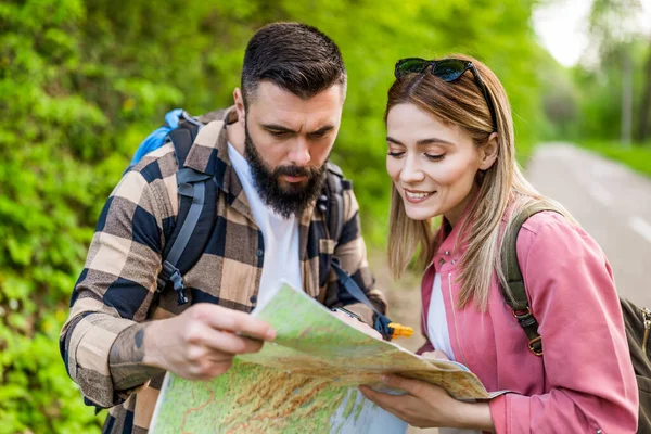 stock image Happy couple hiking in nature and looking at map. Couple enjoying their vacation.