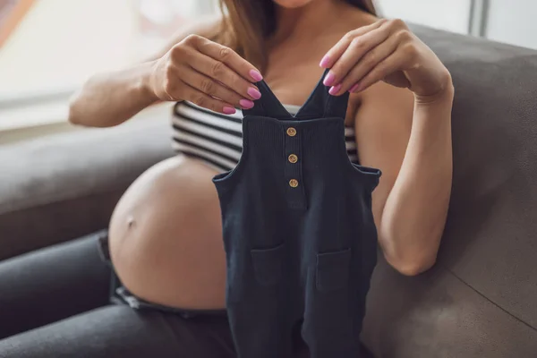Gravid Kvinna Avkopplande Hemma Hon Sitter Sängen Och Håller Babykläder — Stockfoto