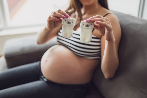 Mujer Embarazada Relajándose Casa Ella Está Sentada Cama Sosteniendo Calcetines —  Fotos de Stock