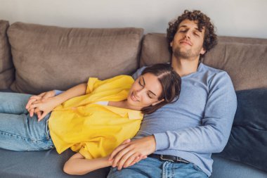 Evdeki mutlu genç çiftin portresi. Kanepede dinleniyorlar..