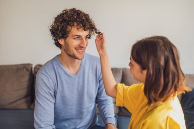 Aşık genç çiftin portresi. Kadın, erkeğin kıvırcık saçlarıyla oynuyor..