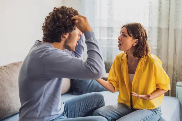 stock image Man and woman are sitting at sofa and arguing. Relationship problems.