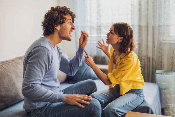 stock image Man and woman are sitting at sofa and arguing. Relationship problems.