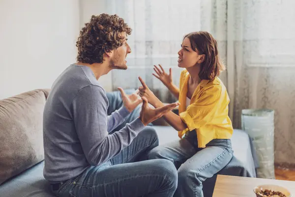 stock image Man and woman are sitting at sofa and arguing. Relationship problems.