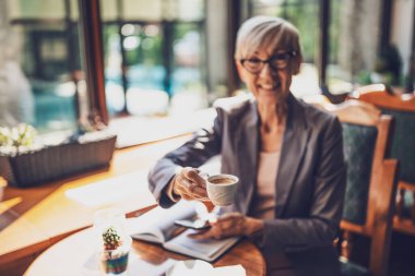Olgun kadın kafede oturuyor ve dinleniyor. Kahve içiyor.. 
