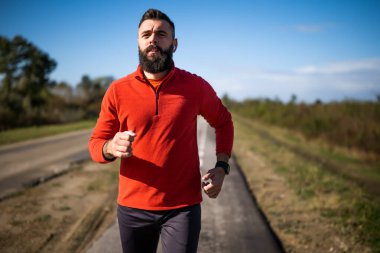 Yetişkin adam güneşli bir günde dışarıda koşuyor..