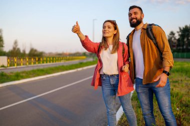 Yol kenarında otostop çeken mutlu çift arabayı durdurmaya çalışıyor..