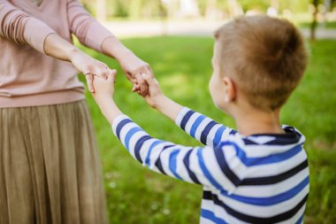 Mutlu anne parkta oğluyla oynuyor. El ele tutuşuyorlar..
