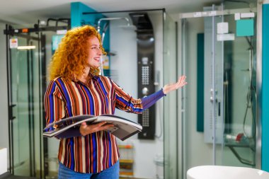 Banyo mağazasındaki satıcının portresi. Mutlu kızıl saçlı kadın banyoda çalışıyor. Satış mesleği.