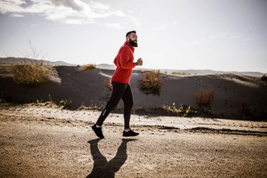 Yetişkin adam güneşli bir günde dışarıda koşuyor..