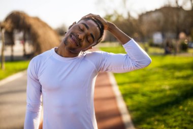 Genç Afro-Amerikan bir adam şehirde egzersiz yapıyor. Vücudunu esnetiyor..