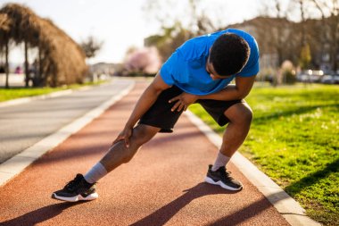 Genç Afro-Amerikan bir adam şehirde egzersiz yapıyor. Vücudunu esnetiyor..