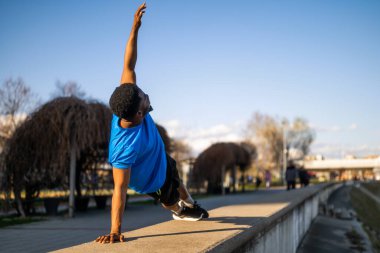 Genç Afro-Amerikan bir adam şehirde egzersiz yapıyor. Vücudunu esnetiyor..