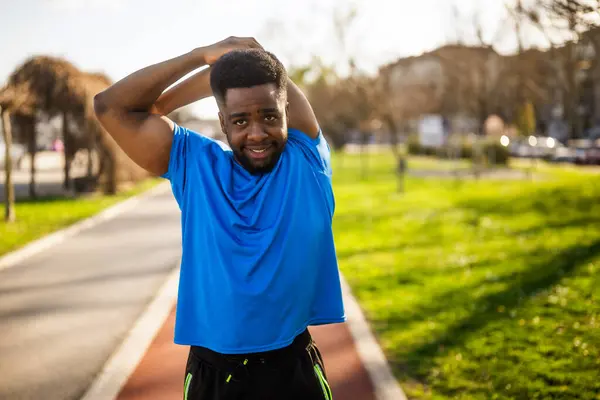 アフリカ系アメリカ人の若者が市内で運動している 彼は体を伸ばしている — ストック写真