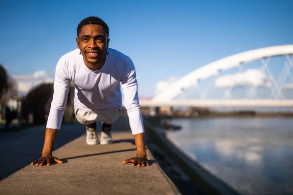 アフリカ系アメリカ人の若者が市内で運動している 彼はプッシュアップをしている — ストック写真