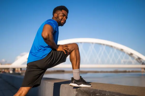 アフリカ系アメリカ人の若者が市内で運動している 彼は体を伸ばしている — ストック写真