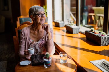 Olgun kadın kafede oturuyor ve dinleniyor..