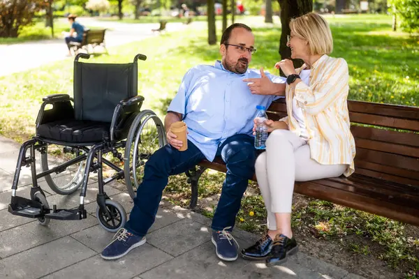 坐轮椅的人在公园和他妈妈呆在一起 图库图片
