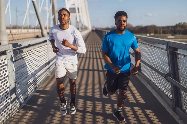 两个非洲裔美国朋友在城里的桥上慢跑 图库图片